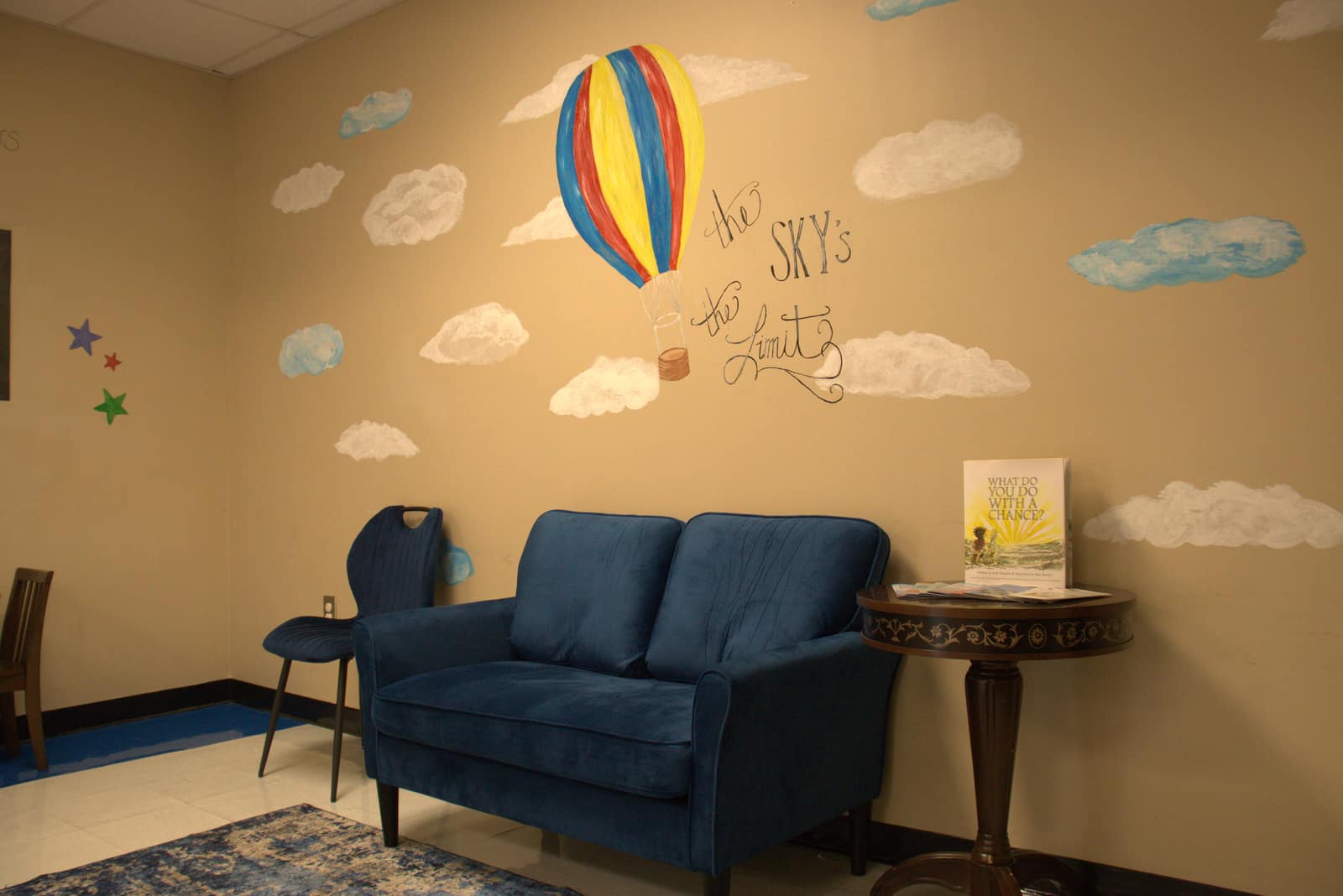 A warm, kid-friendly waiting area in the Southeastern Services Whiteville office, featuring a hand-painted 'the sky's the limit' hot-air-balloon mural